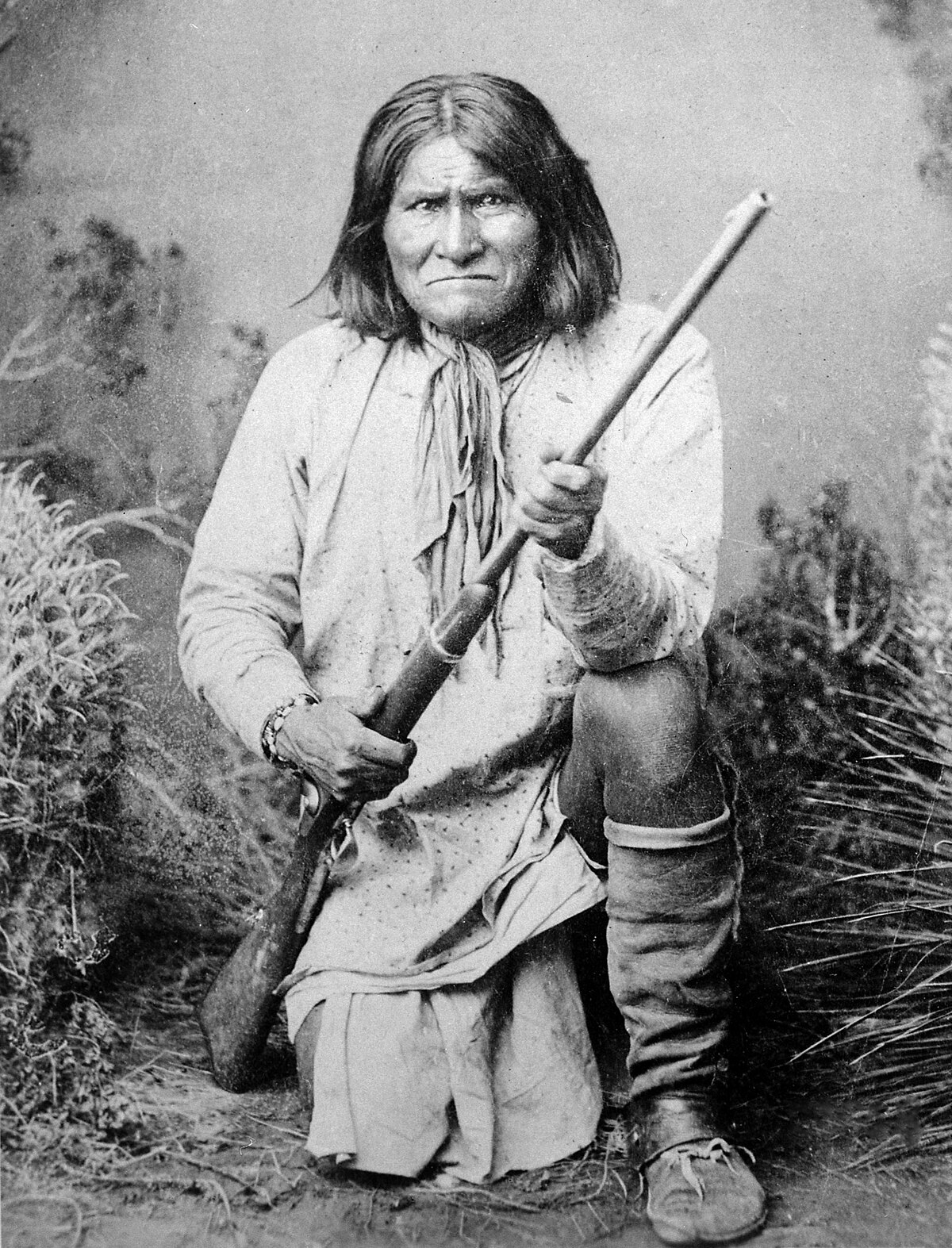1200px-Geronimo_%28Goyathlay%29%2C_a_Chiricahua_Apache%2C_full-length%2C_kneeling_with_rifle%2C_1887_-_NARA_-_530880.jpg